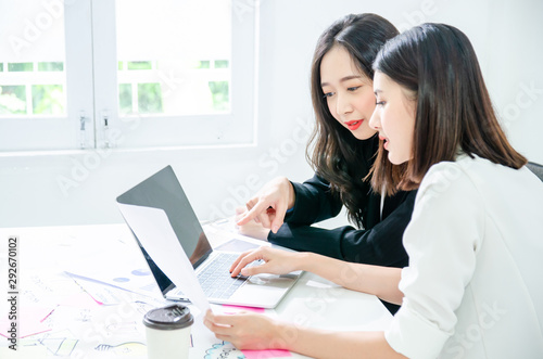 Two young asian women in office working and happy together on desktop