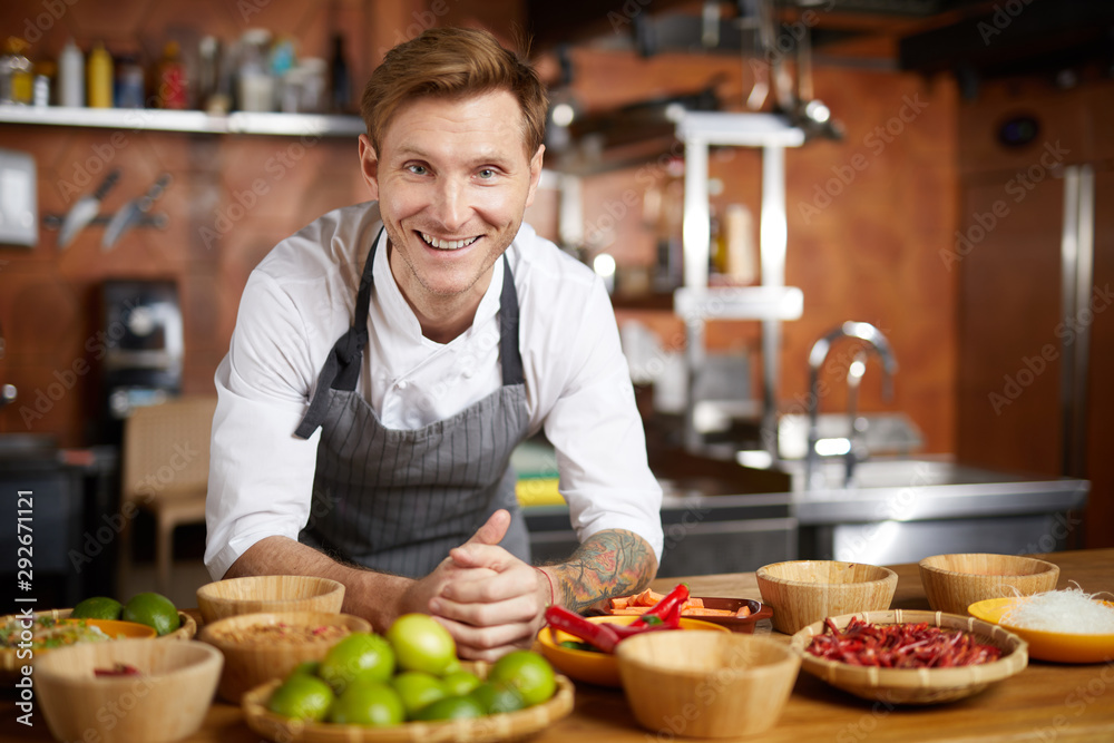 Fototapeta premium Portrait of contemporary chef smiling at camera while posing with spices in restaurant kitchen, copy space