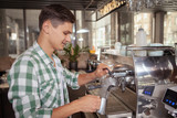 Attractive young male barista working at the coffee shop, preparing a drink on coffee machine. Service, cafe, city life concept