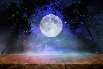 Holidays Halloween concept. Empty rustic table in front of scary and misty night sky and full moon background. Ready for product display montage