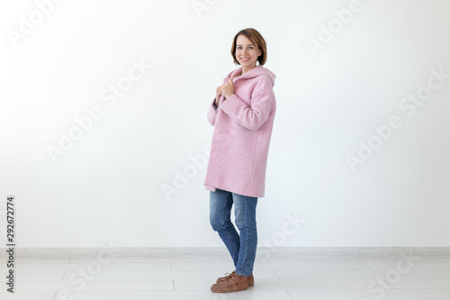 Charming young female model posing on a white background in a designer pink coat. The concept of a unique handicraft design. Advertising space, copyspace