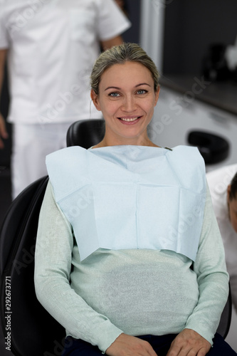 Beautiful pregnant woman at a late date in a black dental chair