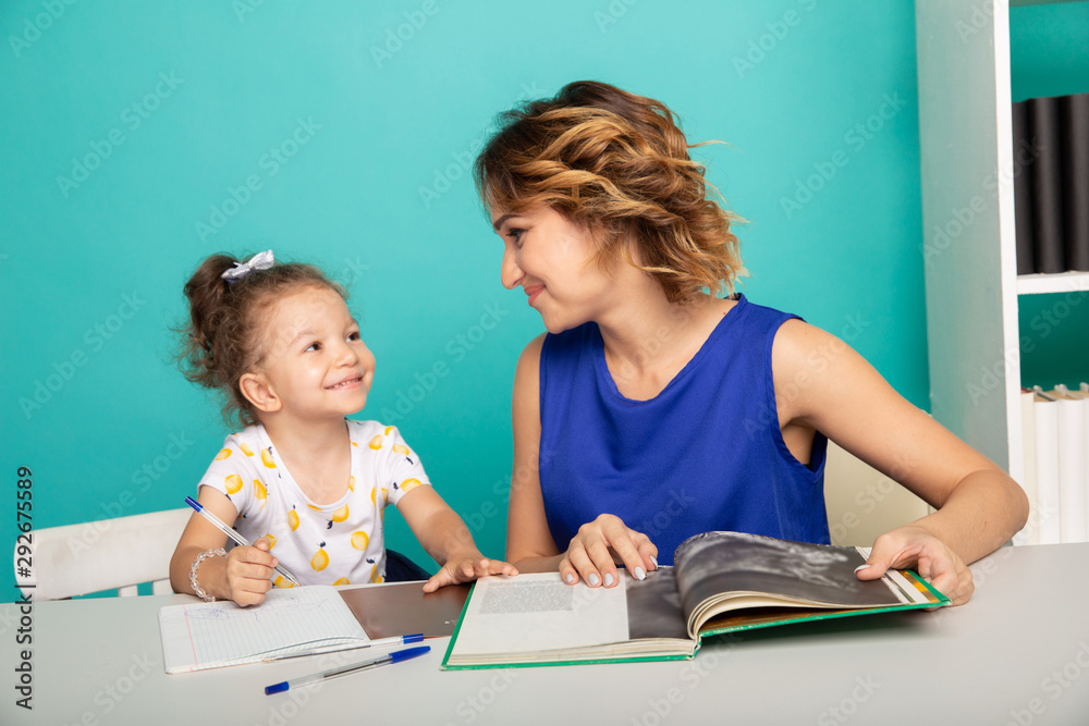 Mother and daughter sitting at the desk doing homework together Mother and daughter sitting at the desk doing homework together