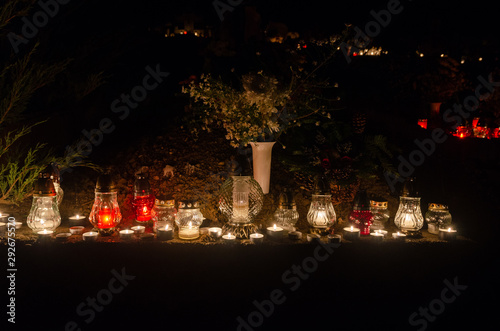 Marble tombstone decorated full of candles and lanterns - in the backgorund flower bouquets - all souls night decoration in a european christian cemetery - original  dark outdoor shot