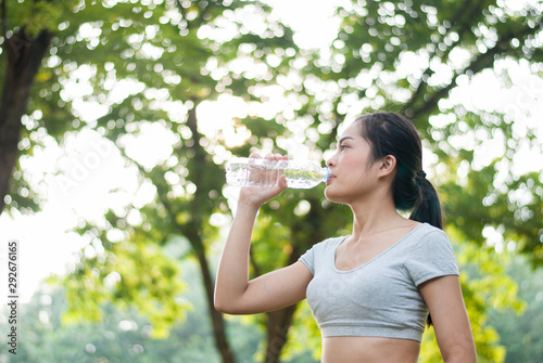 Woman drinking water After exercise is done in the park.