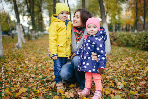 The family walks in the autumn park on a cloudy day.