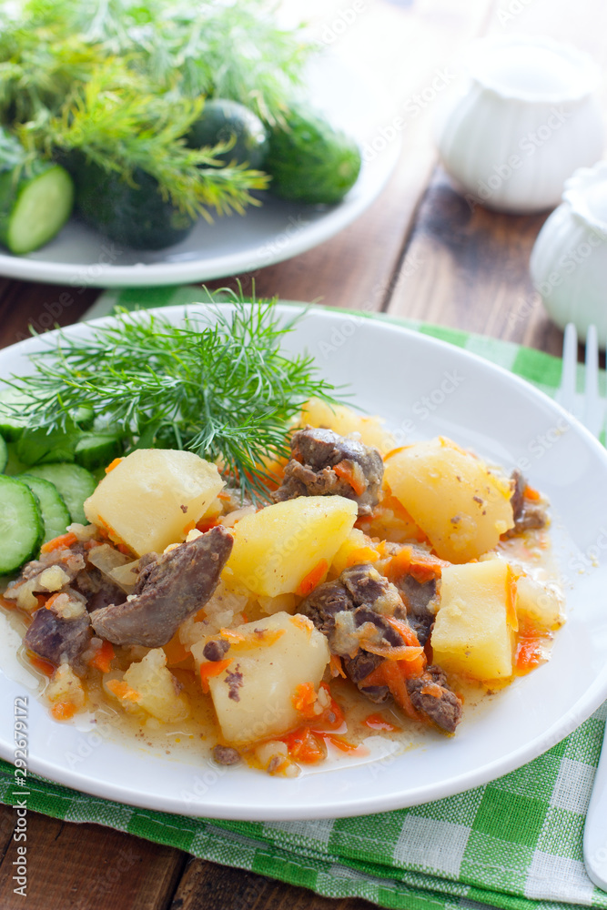 Stewed potatoes with chicken liver and carrots on a white plate, selective focus Stewed potatoes with chicken liver and carrots on a white plate, selective focus