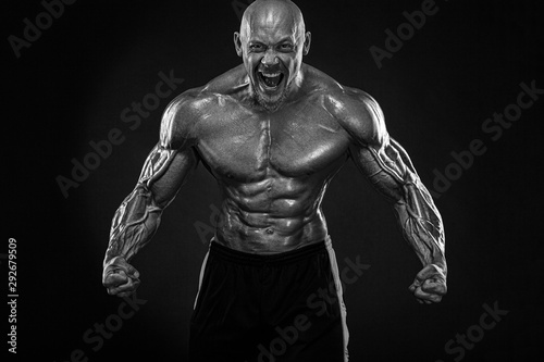 Bodybuilding competitions on the scene. Handsome and fit man sportsmen bodybuilder physique and athlete. Men's fitness motivation. Black and white photo. © Mike Orlov