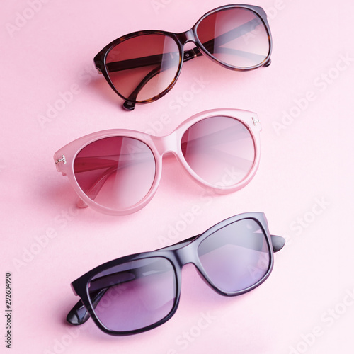 Collection of fashionable sunglasses on pink background. Sunglasses of different shapes and colors flat lay