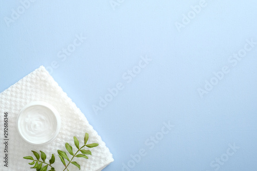 Natural cosmetic cream skincare product wellness and relaxation makeup mask in glass jar with towel on pastel blue background. lat lay, top view, overhead. Skin care and healthcare concept.