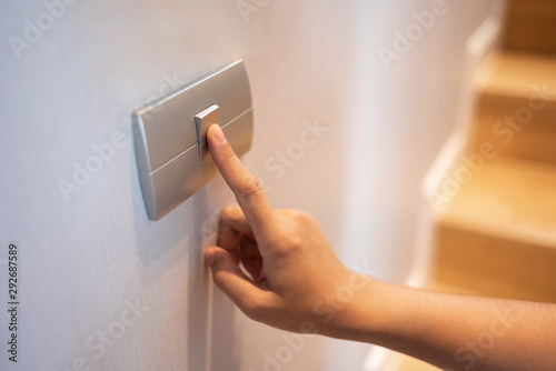 Closeup of finger is turning on or off on light switch at the house.