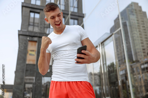 Muscular man looking at his smartphone outside