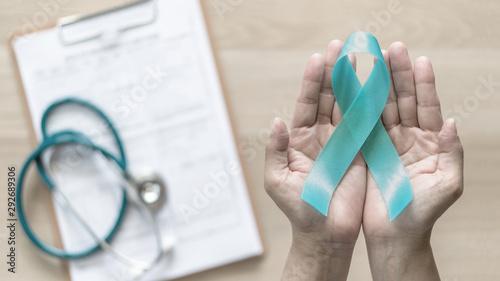 Teal ribbon awareness on woman's hand for Ovarian Cancer, Polycystic Ovary Syndrome (PCOS) disease, Post Traumatic Stress Disorder (PTSD), Tourette's Syndrome, Obsessive Compulsive Disorder (OCD) photo