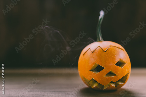 Closeup Photo of Small Carved Pumpkin on the dark Wooden Background with place for text photo