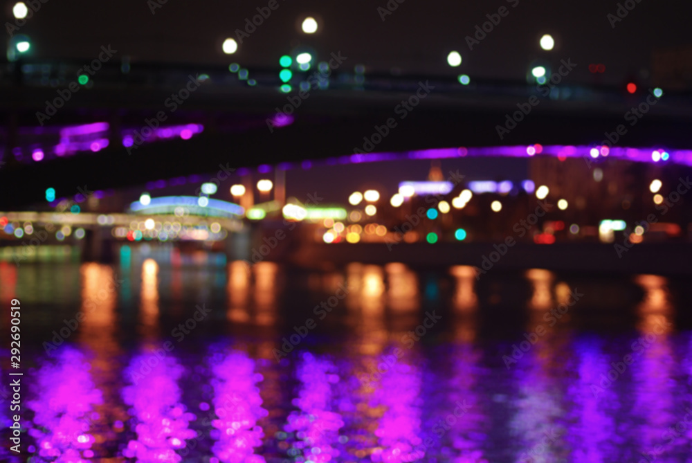 Blurred night cityscape with multi-colored lights and river bridges of Moscow.