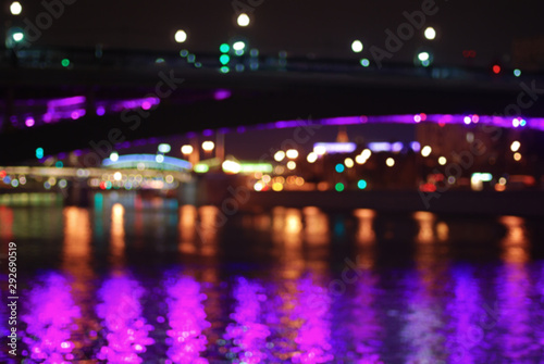 Blurred night cityscape with multi-colored lights and river bridges of Moscow.