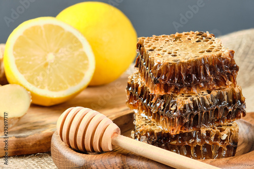 honey in honeycombs on a wooden plate and honey with nuts with lemon and ginger in rustic style on a wooden background. Close-up