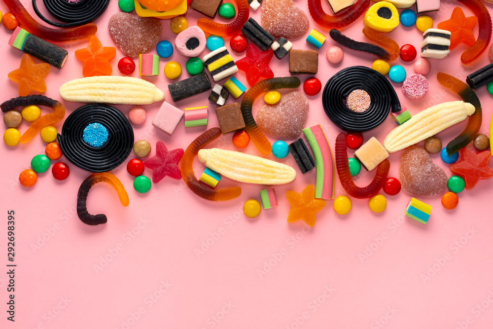 assortment of colourful lollipops and candies on pink like background,  copy space