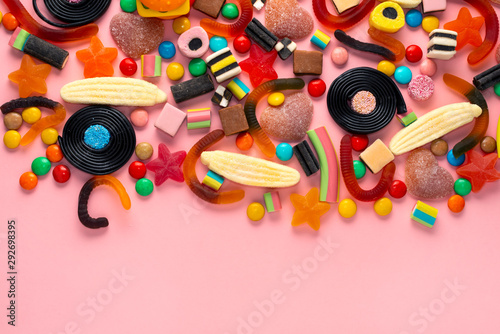 assortment of colourful lollipops and candies on pink like background, copy space