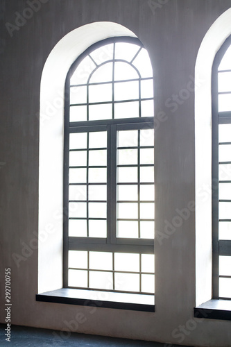 A huge floor window on the entire concrete wall with a wooden window sill. Loft industrial grunge interior. Concrete and dark background. Empty room with large windows and sunlight. Loft style room.