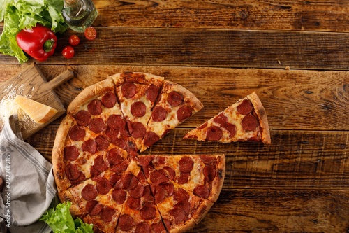 Pepperoni pizza on a wooden table. Still life with ingredients. Top view. Copy space.