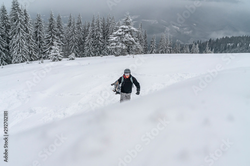 Snowboarder goes up to snow hill. Mountain freeride snowboarding. Winter Carpathians