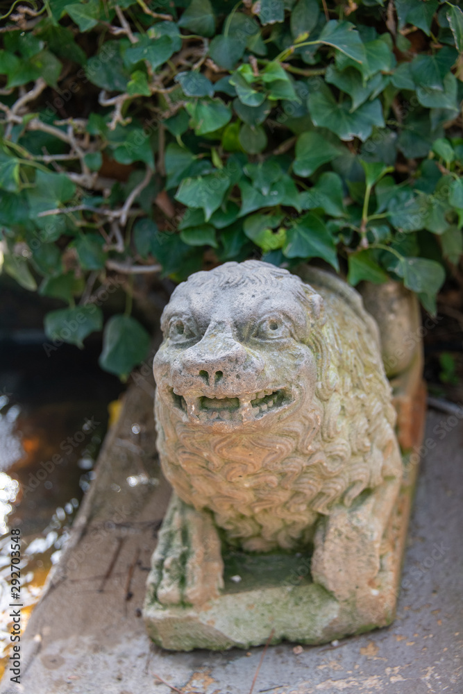 kleine Figur auf einer Mauer unter Farn