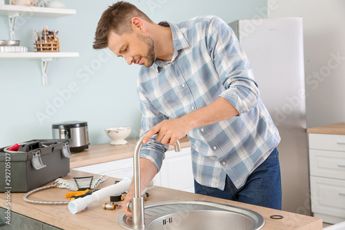 Plumber installing sink in kitchen photo