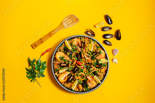 pan with spanish paella with seafood on a yellow background, top view photo