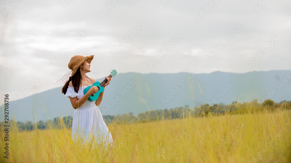 Happy Portrait asian woman playing ukulele guitar on autumn meadow field , lifestyle healthy travel concept Happy Portrait asian woman playing ukulele guitar on autumn meadow field , lifestyle healthy travel concept