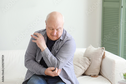 Senior man suffering from pain in elbow at home