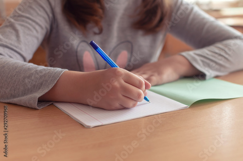 Fototapeta hand of a teenage girl writes with a ballpoint pen in a terad during a lesson at