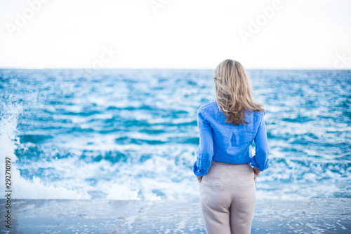 Rear view shot of woman standing at seaside and enjoy looking the sea