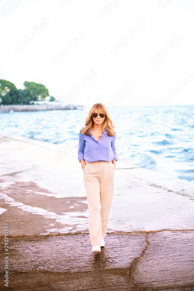 Smiling beautiful woman walking on the beach promenade in a small town