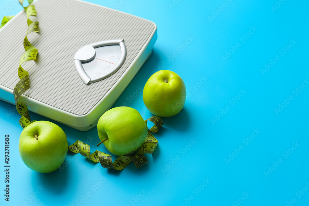 Scales, apples and measuring tape on color background. Weight loss concept Scales, apples and measuring tape on color background. Weight loss concept