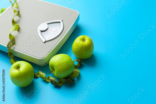 Obraz na plátně Scales, apples and measuring tape on color background