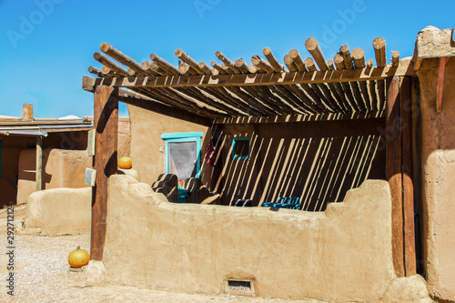 Southwestern US Adobe dwelling with pole ramada sunshade over patio and painted details in turquoise with pumpkins sitting around photo