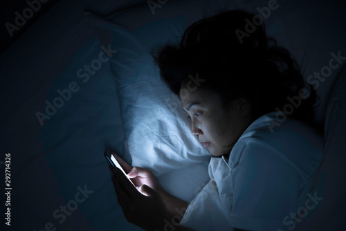 Asian woman play smartphone in the bed at night,Thailand people photo