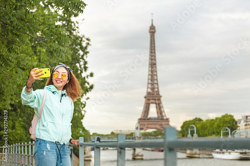 Happy Asian girl traveler makes selfie portrait on mobile phone against Eiffel tower in Paris © EdNurg