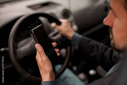 Man looking at mobile phone while driving a car.