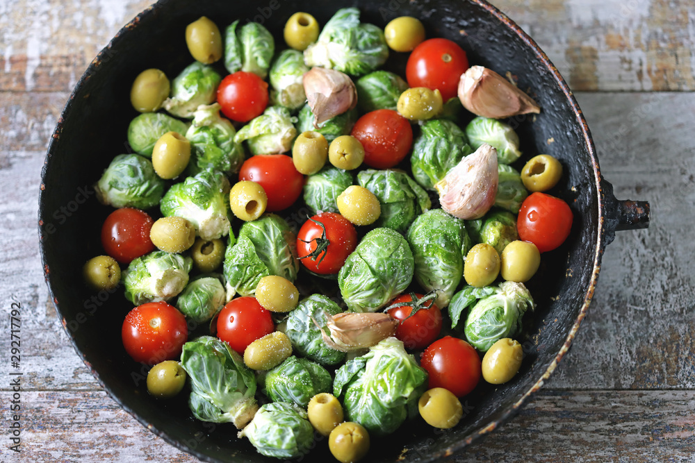 Brussels sprouts in a pan with cherry tomatoes, garlic and olives before baking. Healthy food. Vegan diet. Vegetable pan. Brussels sprouts in a pan with cherry tomatoes, garlic and olives before baking. Healthy food. Vegan diet. Vegetable pan.