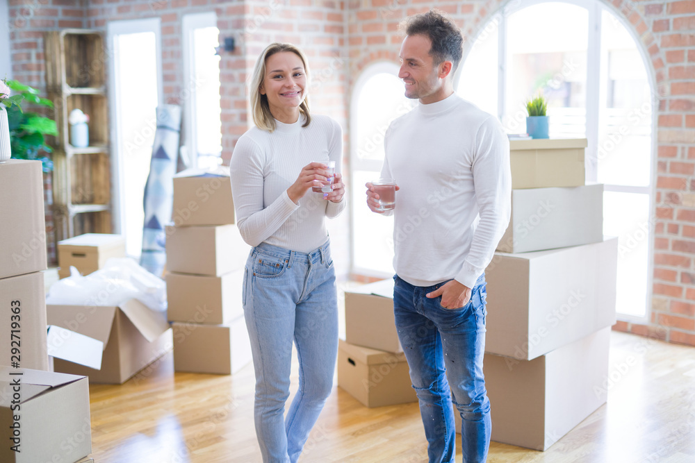 Young beautiful couple standing drinking cup of coffee at new home around cardboard boxes Young beautiful couple standing drinking cup of coffee at new home around cardboard boxes