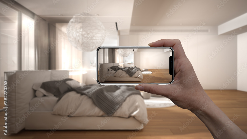 Hand holding smart phone, AR application, simulate furniture and interior design products in real home, architect designer concept, blur background, modern bedroom with bathroom Hand holding smart phone, AR application, simulate furniture and interior design products in real home, architect designer concept, blur background, modern bedroom with bathroom