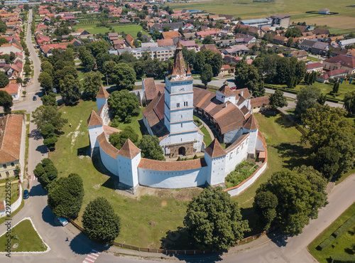 Aerial view of fortified church surrounded powerful thick walls in Transylvania overlooking the village in a beautiful summer day. Romania. photo