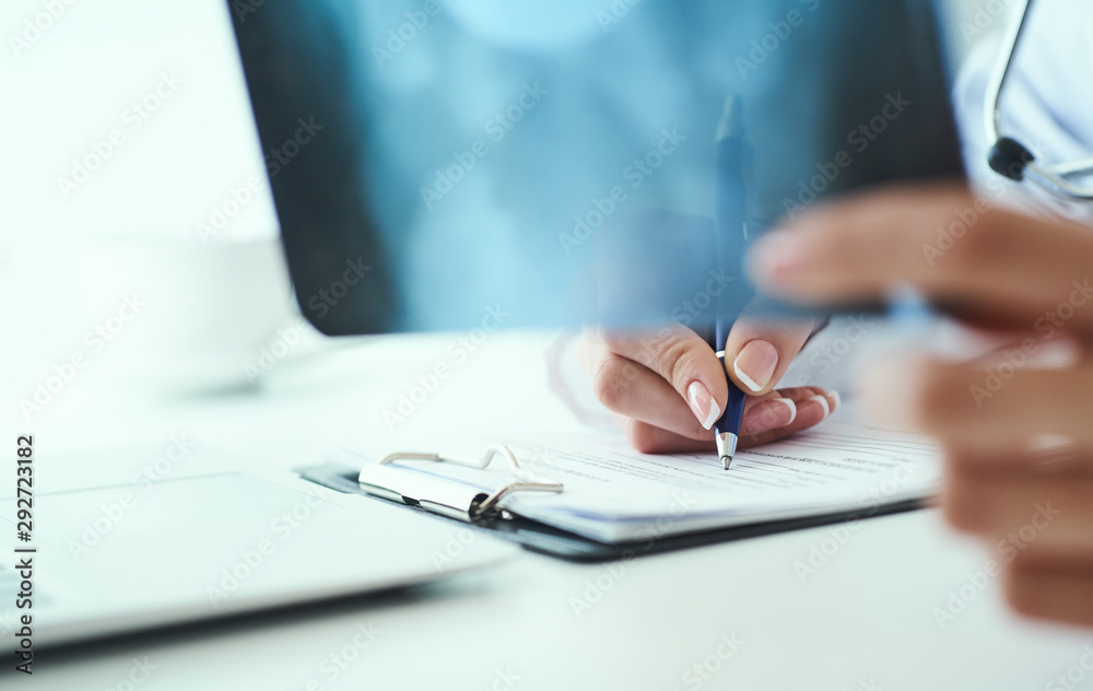 Obraz premium Close up of female doctor holding x-ray or roentgen image and making notes in medical form.