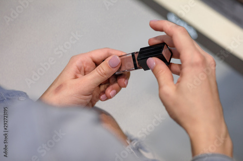 woman customer is testing lipstick by putting it on her arm in make-up shop.