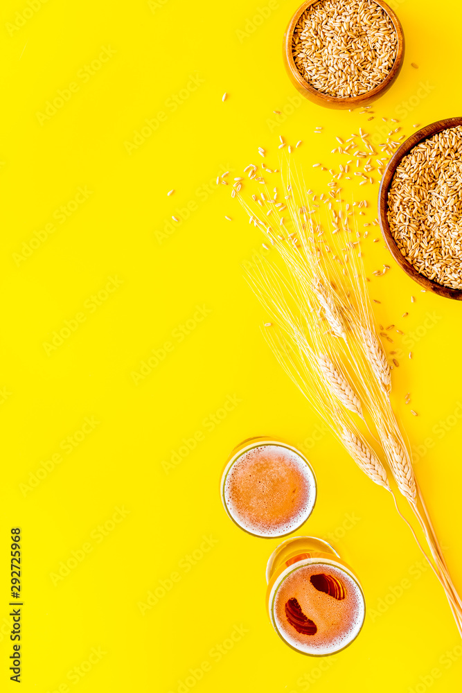 Fototapeta Beer ingredients. Barley near beer glasses on yellow background top view copy space