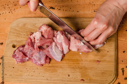 Female hands with a knife in their hand cut fresh meat on a table photo