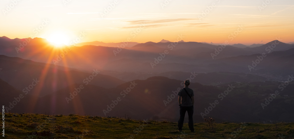Hiker and sun at sunset over the mountains of Gipuzkoa