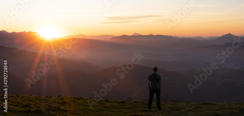 Hiker and sun at sunset over the mountains of Gipuzkoa